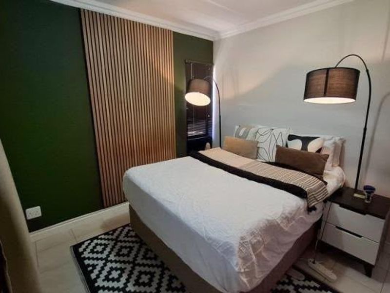 A well-maintained bedroom featuring a modern timber slat feature wall, neutral tiled flooring, and decorative coving.