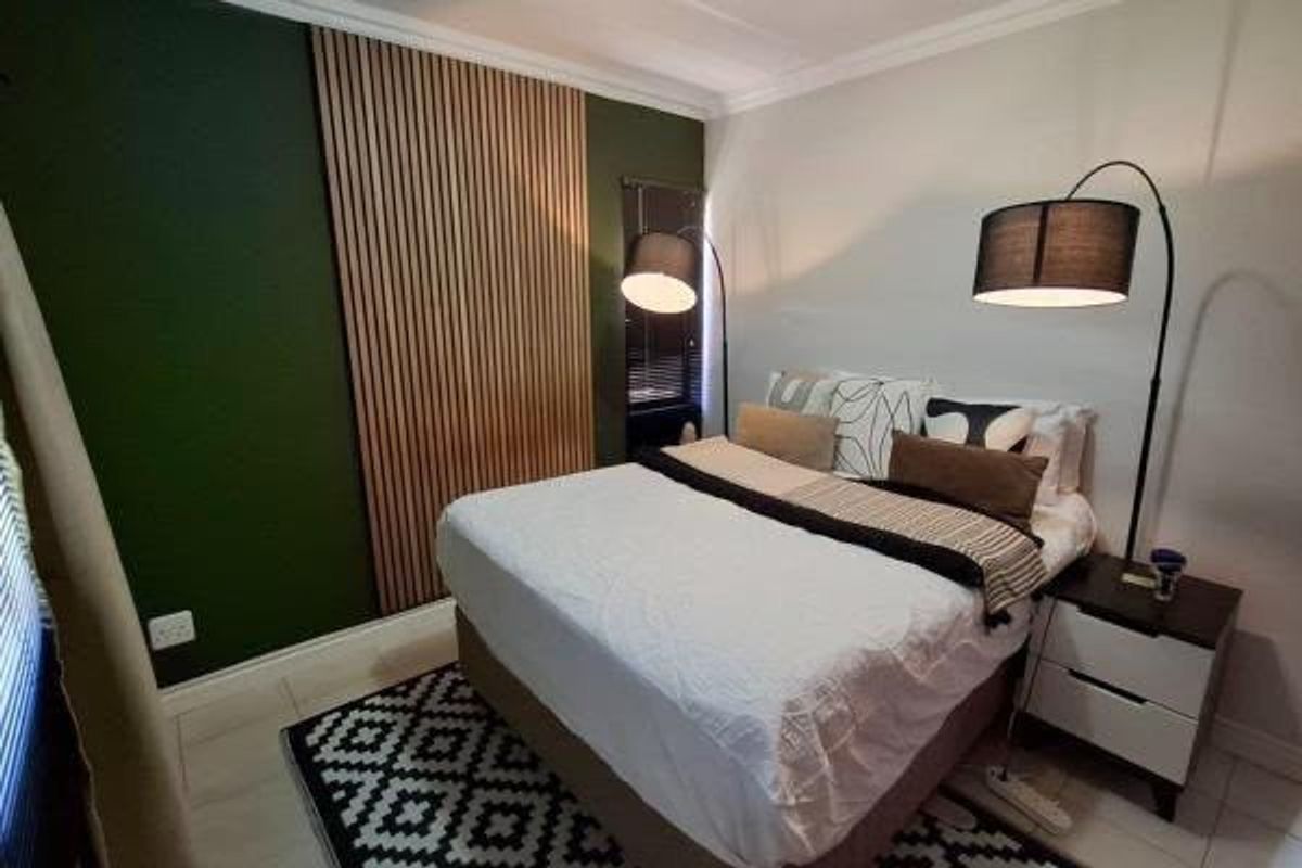 A well-maintained bedroom featuring a modern timber slat feature wall, neutral tiled flooring, and decorative coving.
