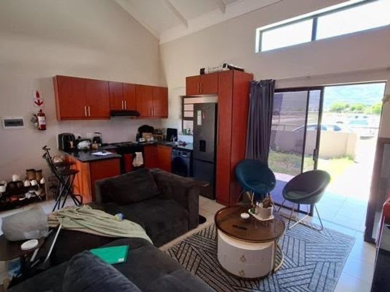 Open-plan living area featuring a kitchen with built-in cabinetry, vaulted ceilings, and sliding glass doors leading to an outdoor space.