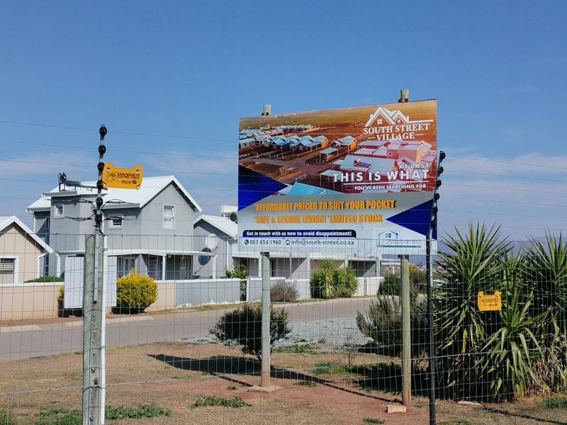 Street view of the South Street Village townhouse development, featuring secure perimeter fencing and established residential units.