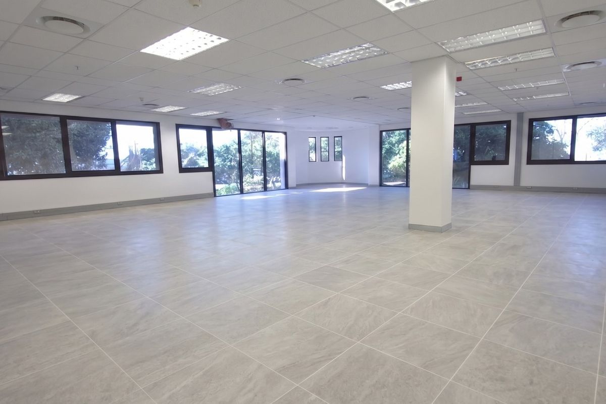 Spacious open-plan retail or office area featuring large windows, modern tiled flooring, and a suspended ceiling with recessed lighting.