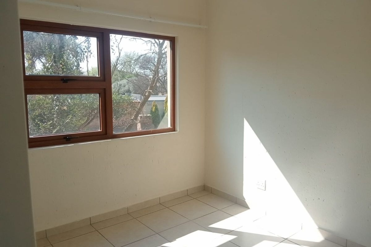 A bright, empty bedroom featuring neutral tiled flooring and a timber-framed window, offering a blank canvas for personalization.