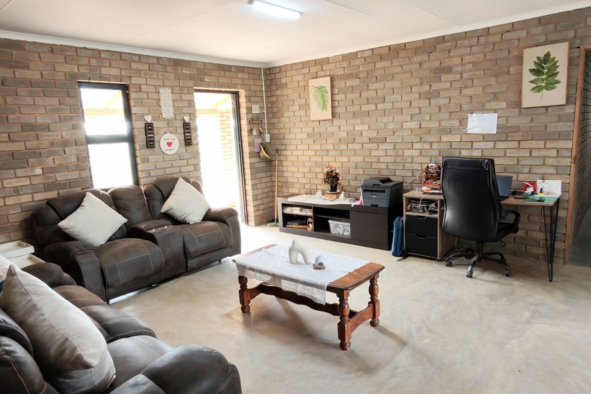 Spacious living area featuring exposed brick walls and durable concrete flooring, offering a versatile layout suitable for a lounge and home office setup.