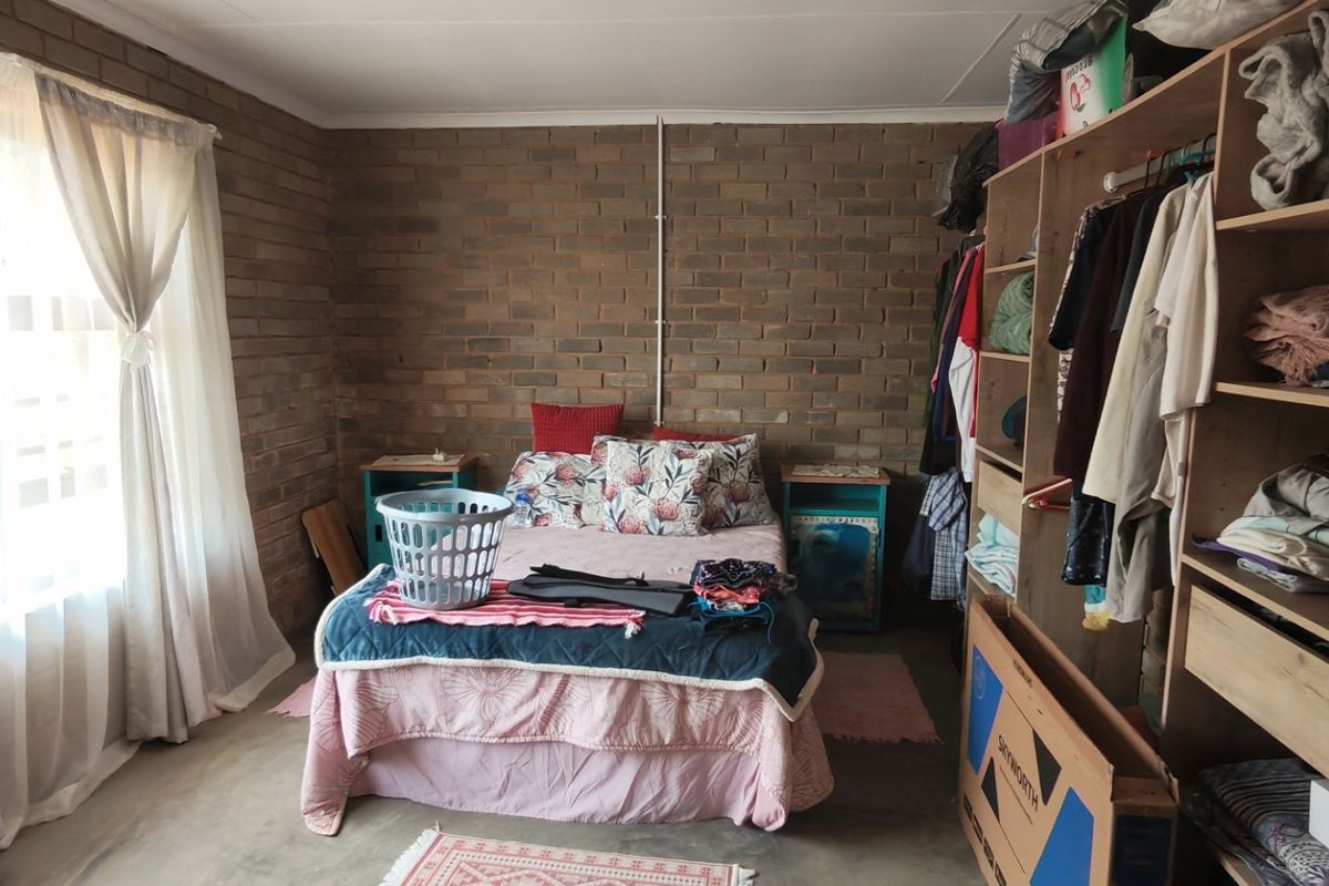 A bedroom featuring exposed brick walls and a large built-in shelving unit, offering a rustic aesthetic with functional storage space.