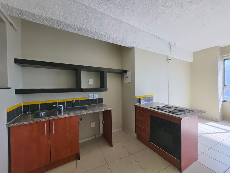 A functional kitchen featuring built-in cabinetry, granite countertops, a built-in oven with hob, and tiled flooring in an open-plan layout.