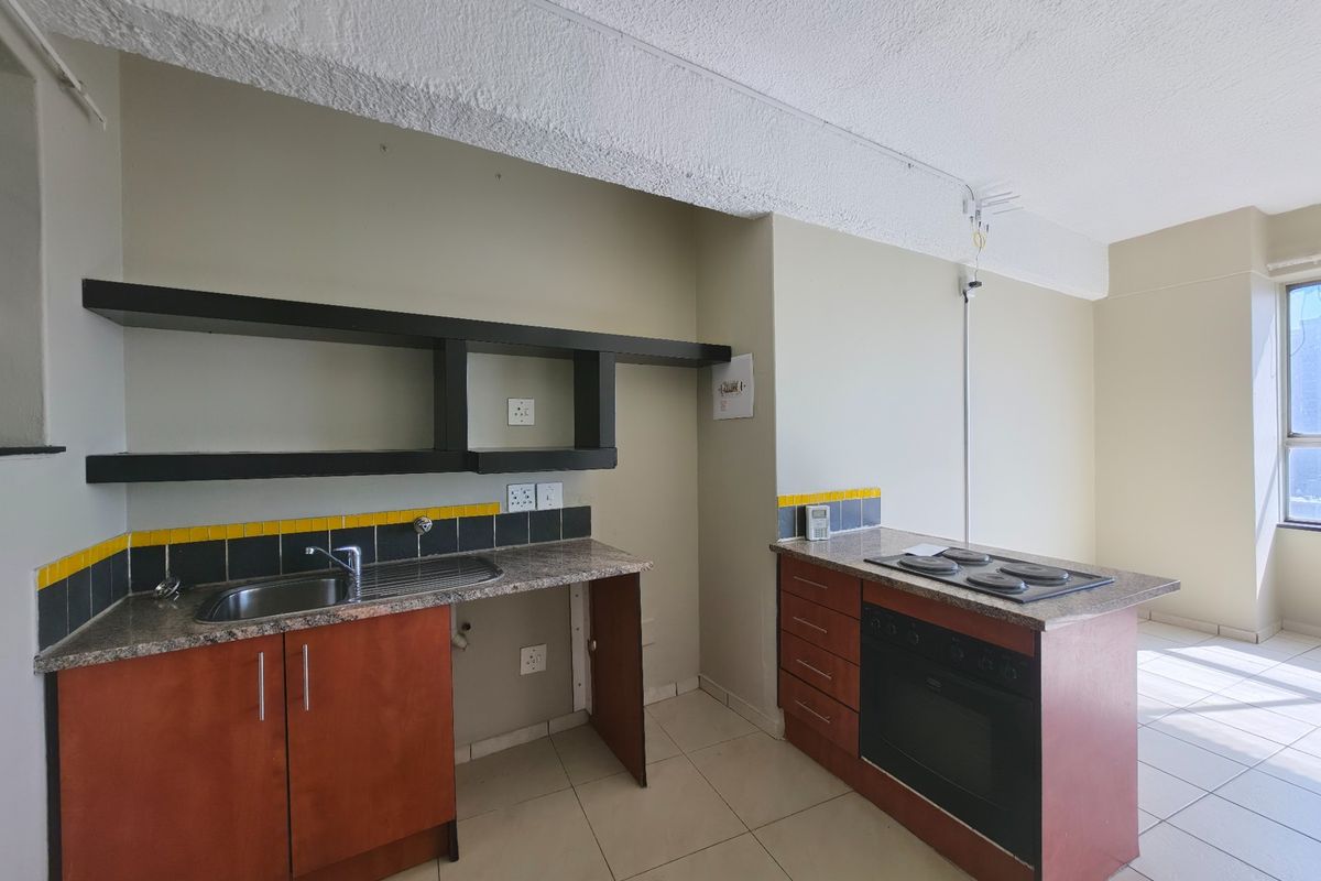 A functional kitchen featuring built-in cabinetry, granite countertops, a built-in oven with hob, and tiled flooring in an open-plan layout.