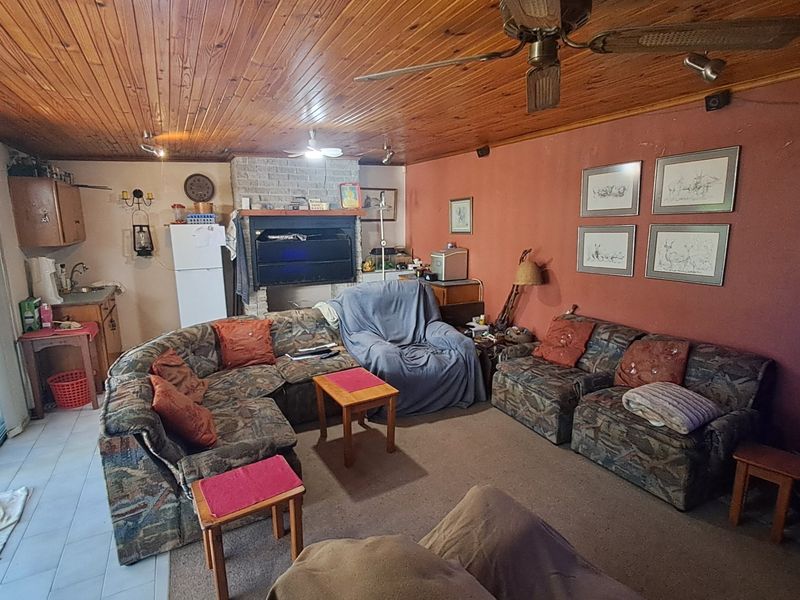 Open-plan living area featuring a brick fireplace, timber-clad ceiling, and direct access to the patio through sliding glass doors.