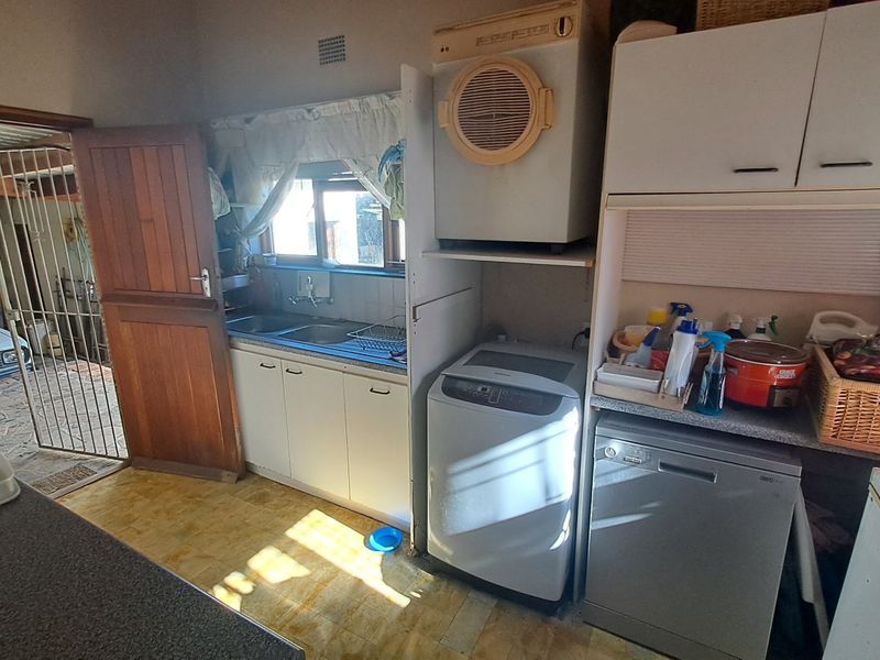 Functional laundry area featuring built-in cabinetry, a double sink, and dedicated space for laundry appliances with direct access to the exterior.