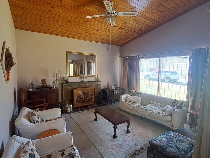 Spacious living room featuring a stone fireplace, vaulted timber-clad ceiling, and large sliding glass doors providing natural light.