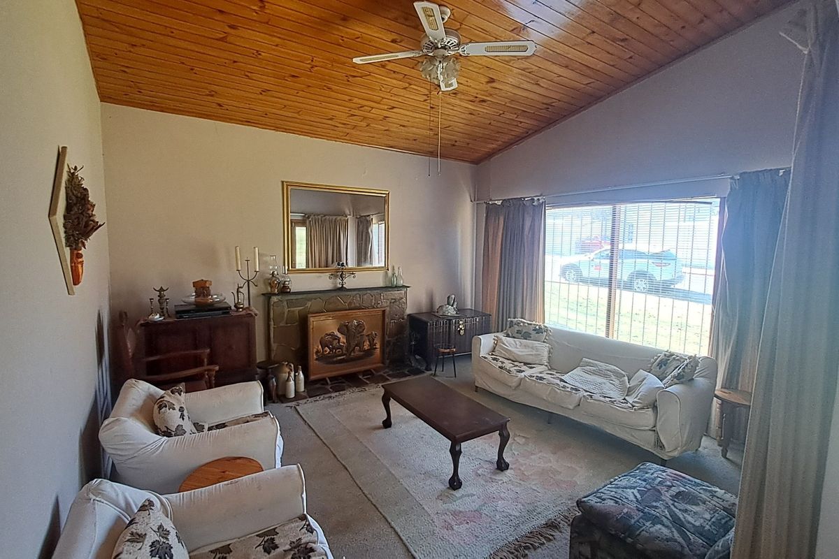 Spacious living room featuring a stone fireplace, vaulted timber-clad ceiling, and large sliding glass doors providing natural light.