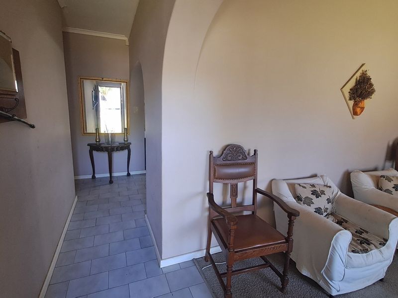 A neutral-toned hallway featuring tiled flooring and an arched architectural transition leading into the adjacent living space.