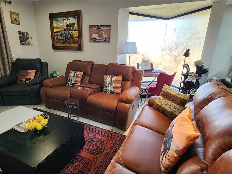 A comfortable living room featuring large bay windows that provide natural light and a view of the outdoors.