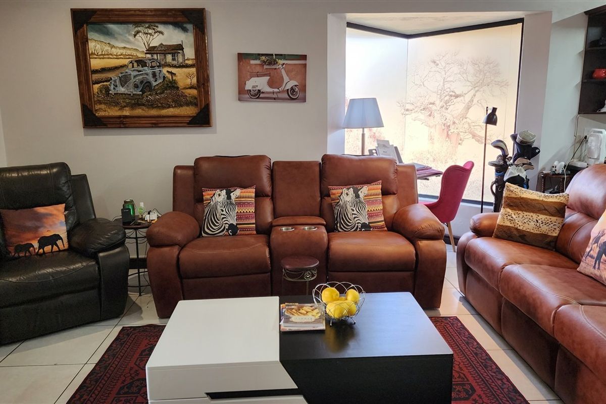 A comfortable living room featuring tiled flooring and a large window that allows for natural light.