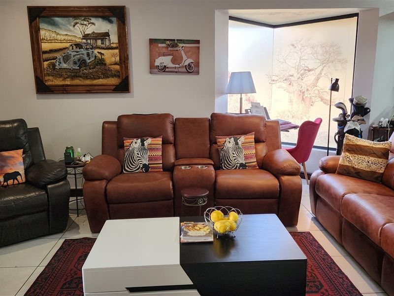A comfortable living room featuring tiled flooring and a large window that allows for natural light.