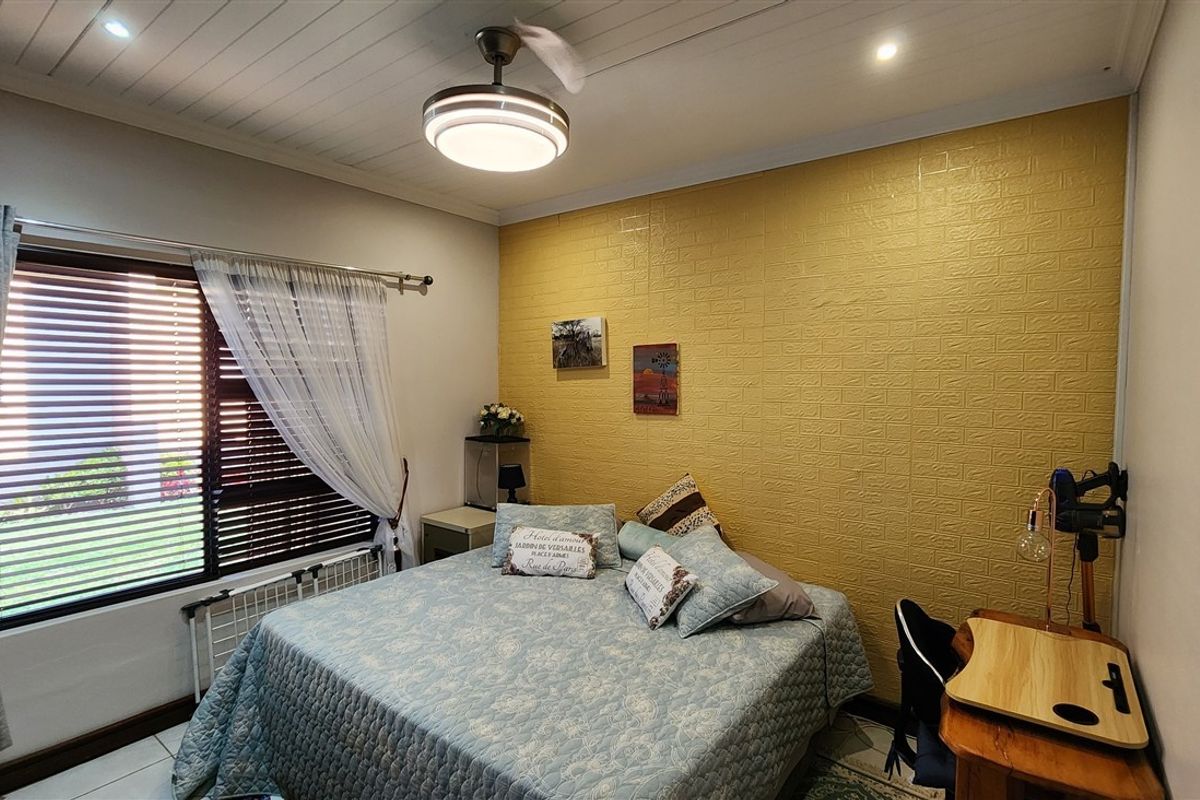 A bedroom featuring a textured yellow accent wall, tiled flooring, recessed lighting, and a ceiling fan with integrated light.