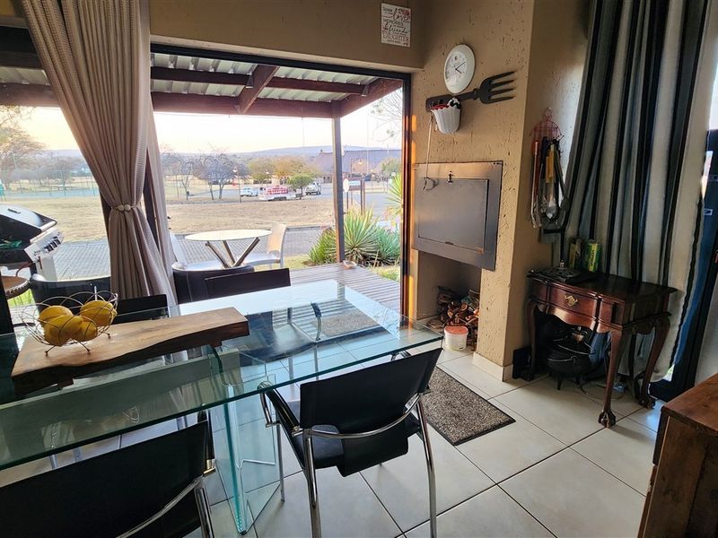 Covered patio area featuring a built-in braai, tiled flooring, and large sliding glass doors providing seamless access to the outdoor space.