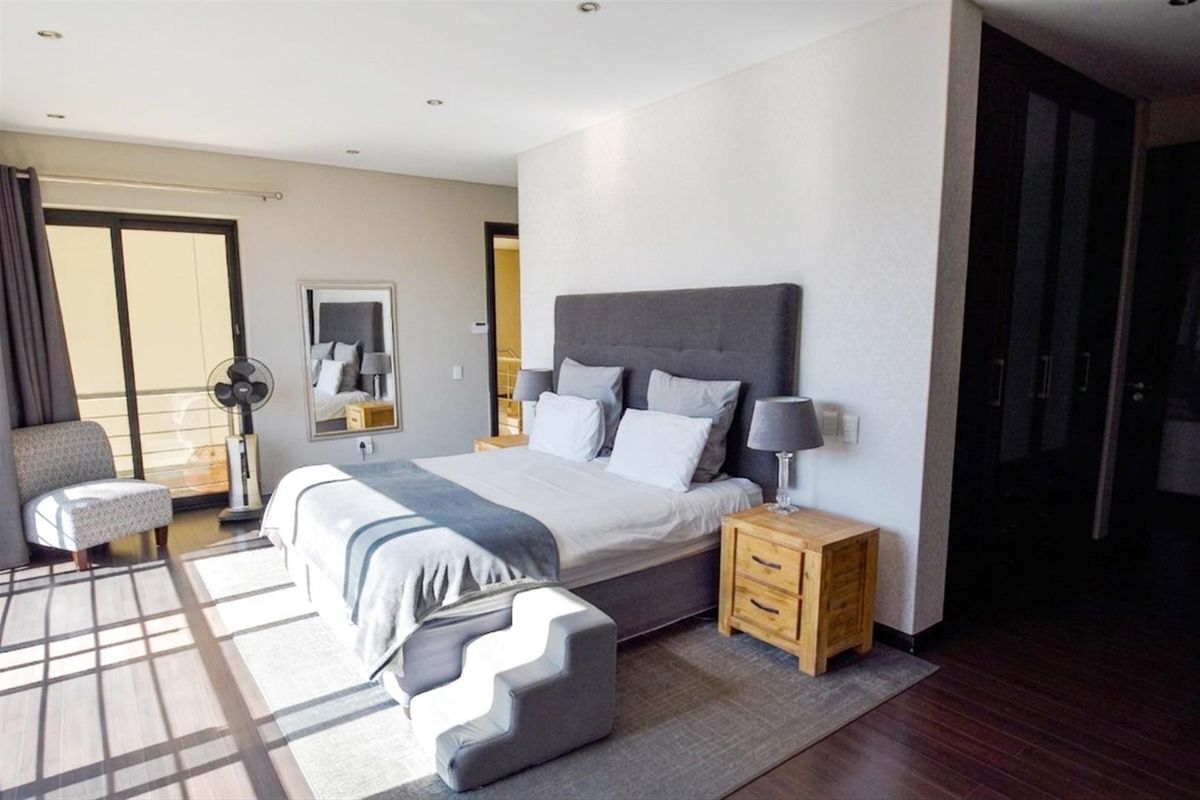 Spacious bedroom featuring laminate flooring, recessed downlights, and a sliding glass door providing access to an outdoor area.