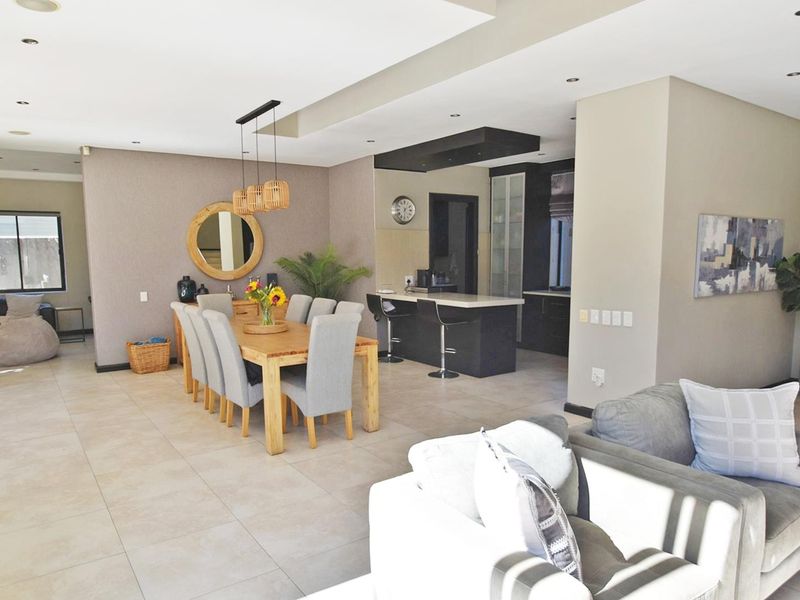 Spacious open-plan living and dining area featuring modern tiled floors, recessed lighting, and a contemporary kitchen with a central island and stone countertops.