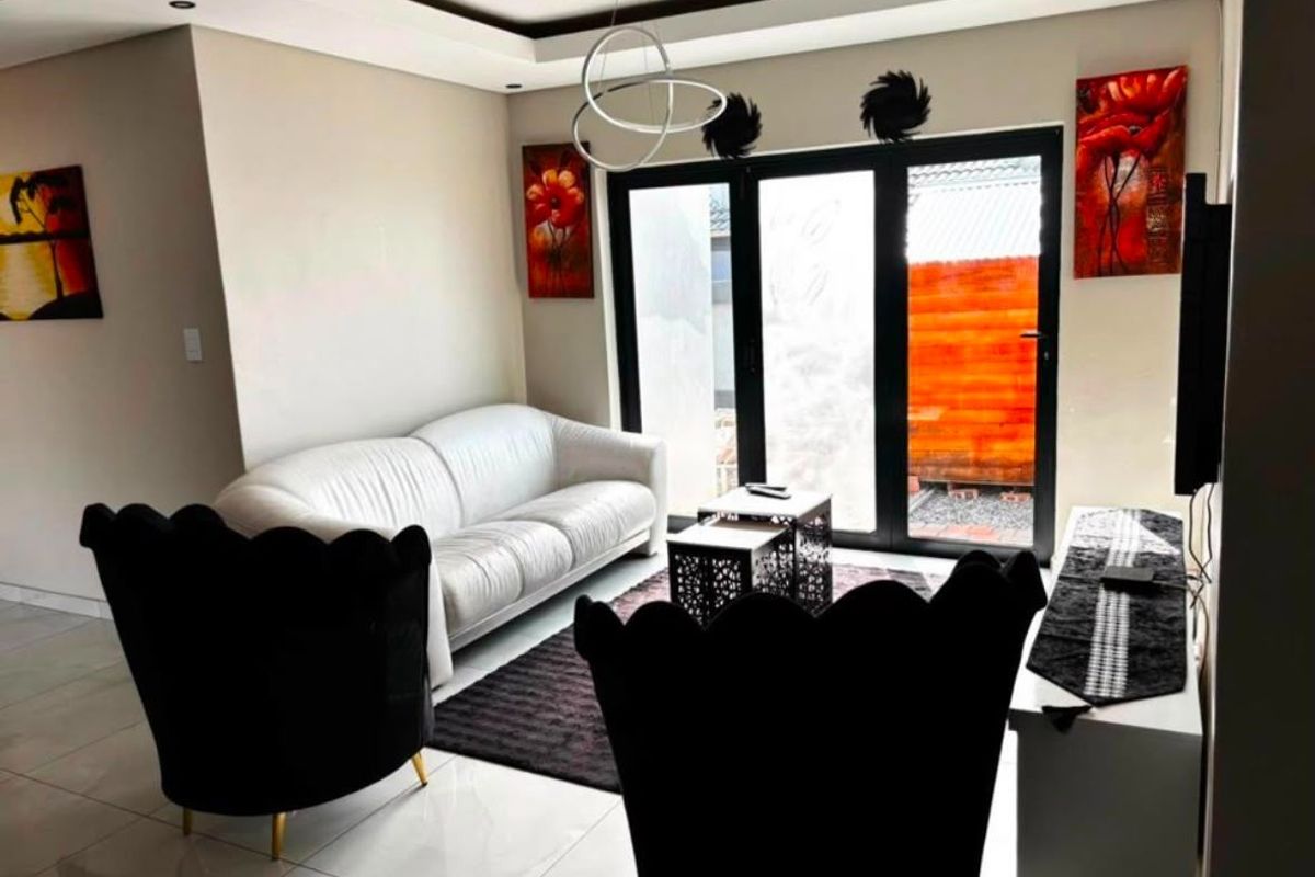 Modern living room featuring tiled flooring, a recessed ceiling design, and black aluminium sliding doors providing access to the outdoor area.