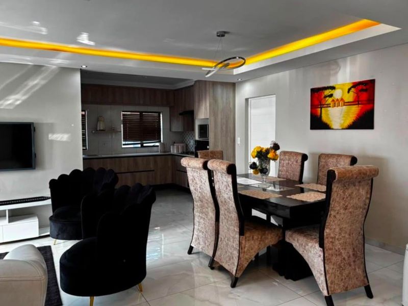 Modern open-plan living and dining area featuring tiled floors, recessed ceiling lighting, and a contemporary kitchen with integrated cabinetry.