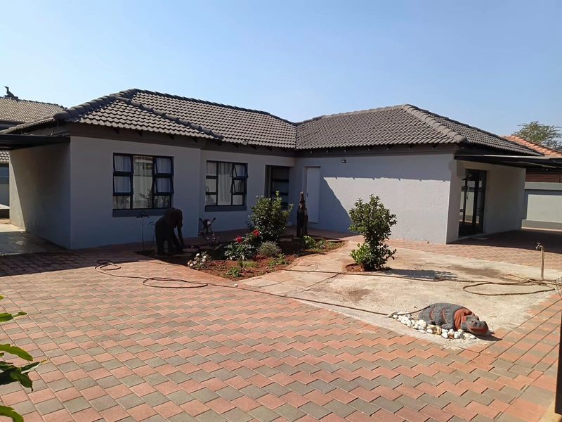 Front exterior view of a single-story house featuring a paved driveway, tiled roof, and a small landscaped garden area.