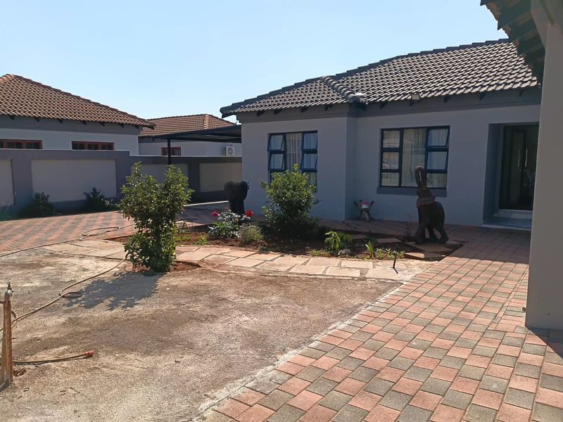 Front exterior view of a residential house featuring a paved driveway, tiled roof, and established boundary walls.