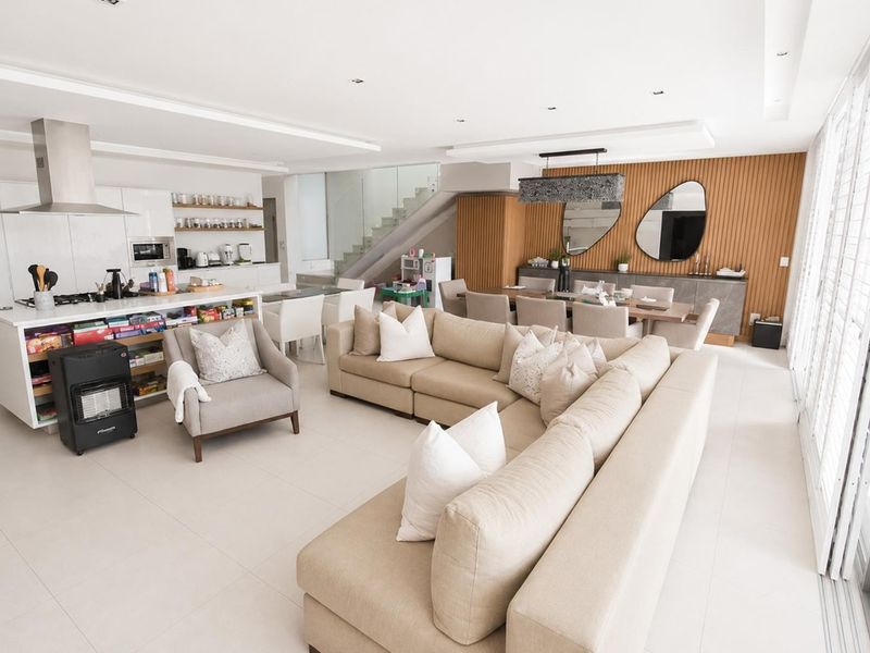 Spacious open-plan living, dining, and kitchen area featuring modern finishes, a central island, and elegant timber wall paneling.
