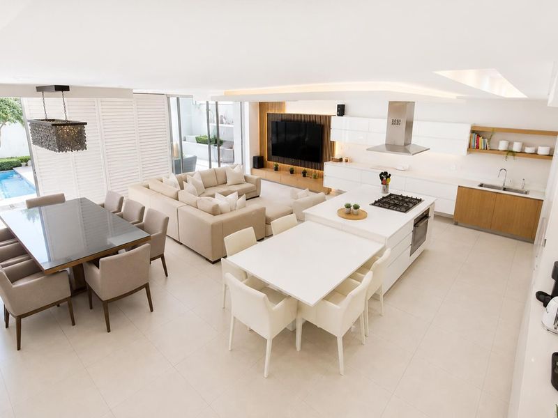 Spacious open-plan living area featuring a modern kitchen with island, dining space, and seamless flow to the outdoor patio and pool area.