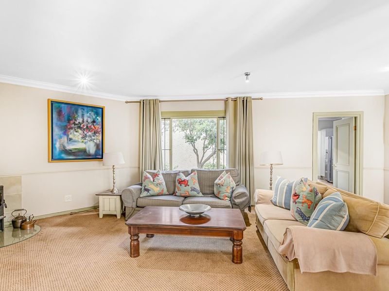 A comfortable living room featuring a wood-burning stove on a glass hearth, crown molding, and wainscoting, providing a cozy and traditional atmosphere.