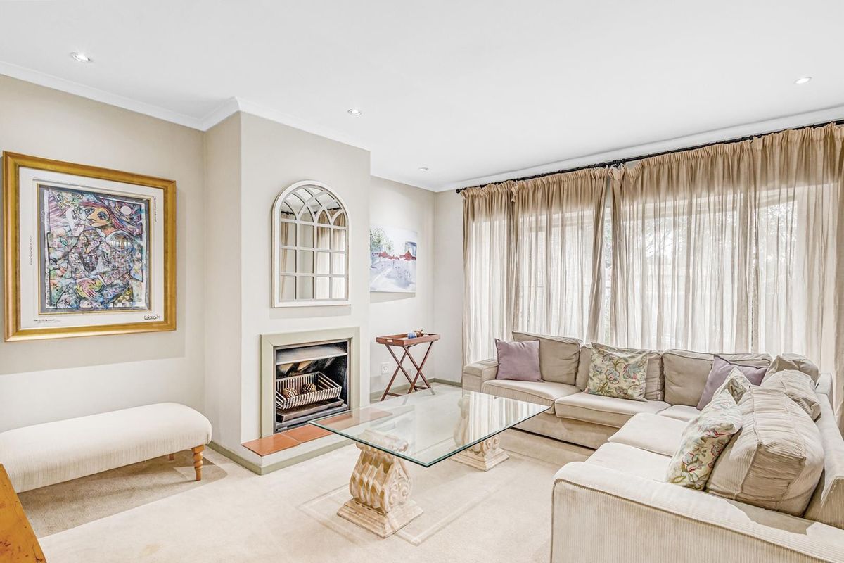 A bright and comfortable living room featuring a built-in fireplace, recessed downlighting, and large windows with floor-to-ceiling curtains.