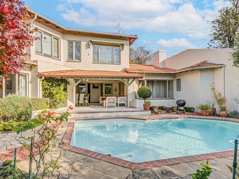 Rear view of the property featuring a swimming pool, paved patio area, and a covered outdoor entertainment space with a tiled roof.