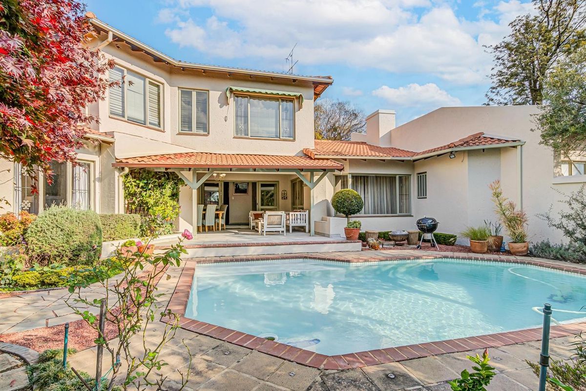 Rear view of the property featuring a swimming pool, paved patio area, and a covered outdoor entertainment space with a tiled roof.