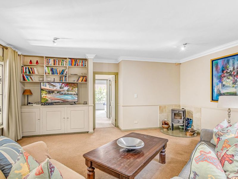 A comfortable living room featuring built-in cabinetry, a cozy fireplace, crown molding, and wainscoting, offering a warm and inviting atmosphere.