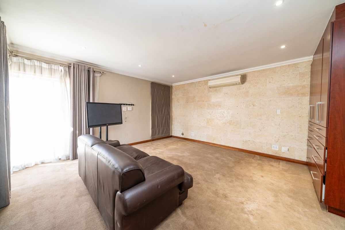 Spacious bedroom featuring a stone accent wall, built-in cabinetry, split-system air conditioning, and direct access to an outdoor area via sliding glass doors.