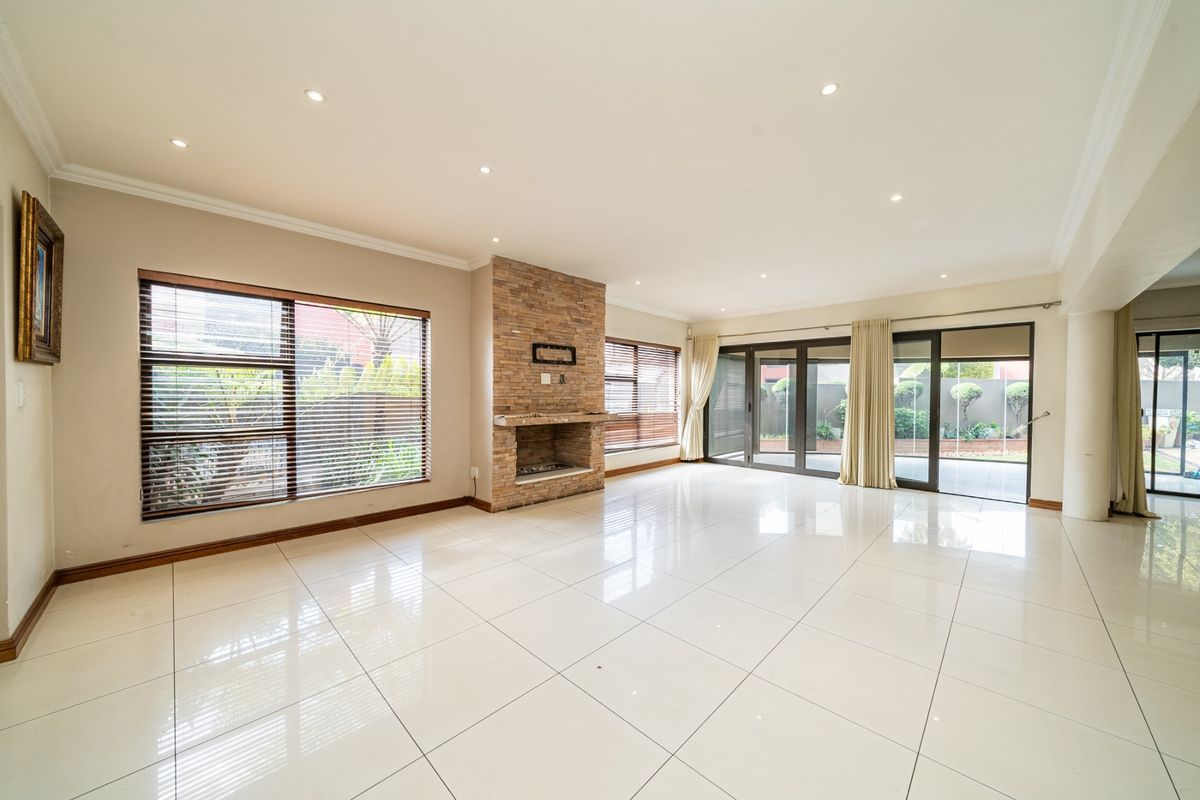 Spacious, light-filled living room featuring polished tile flooring, a prominent stone-clad fireplace, and large sliding glass doors providing seamless access to the outdoor area.