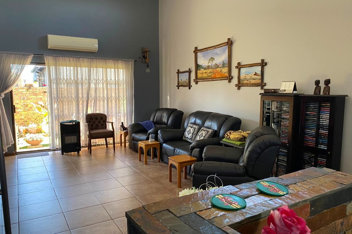 Spacious living room featuring tiled flooring, a split-system air conditioner, and a sliding glass door providing access to the rear patio area.
