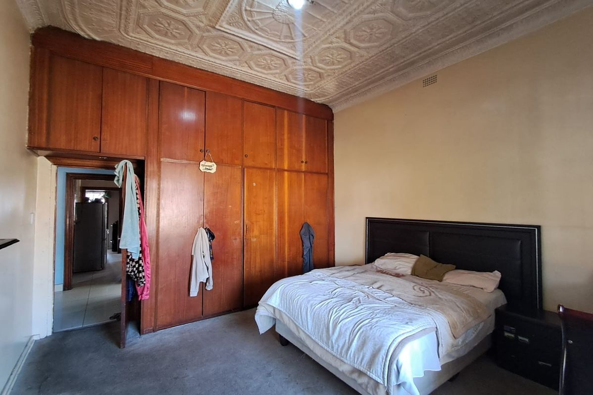 A bedroom featuring classic built-in wooden cabinetry and an ornate pressed metal ceiling, offering a vintage aesthetic with potential for modernization.