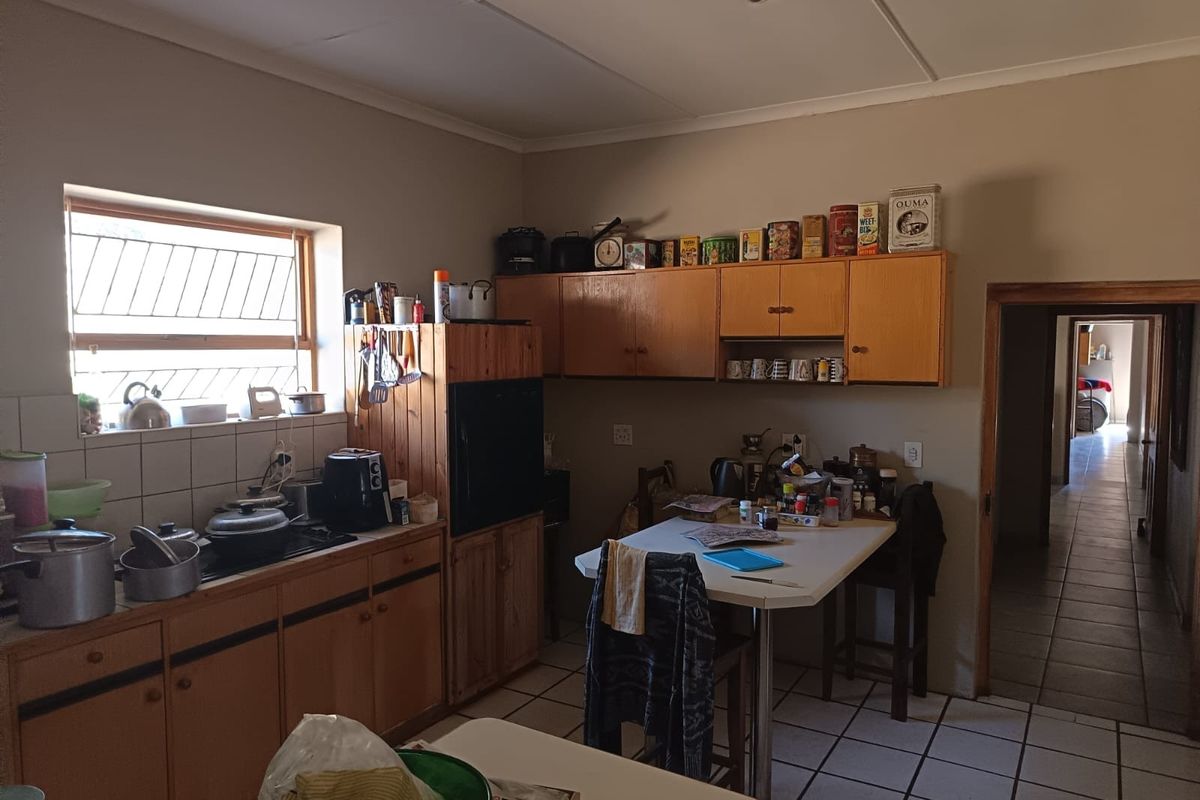 A functional kitchen featuring wooden cabinetry, tiled flooring, and a built-in oven, offering a practical layout with potential for modern updates.