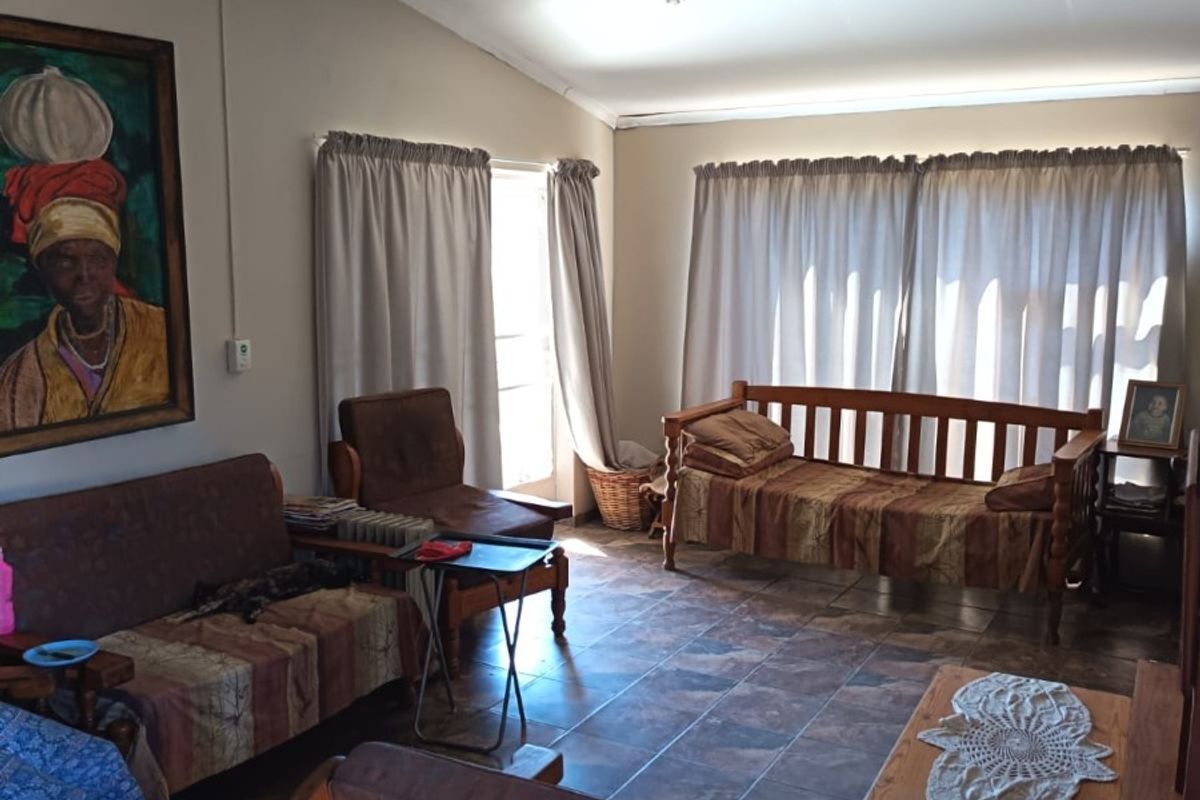 A living room featuring tiled flooring and a ceiling fan, offering a functional space with natural light from the windows.