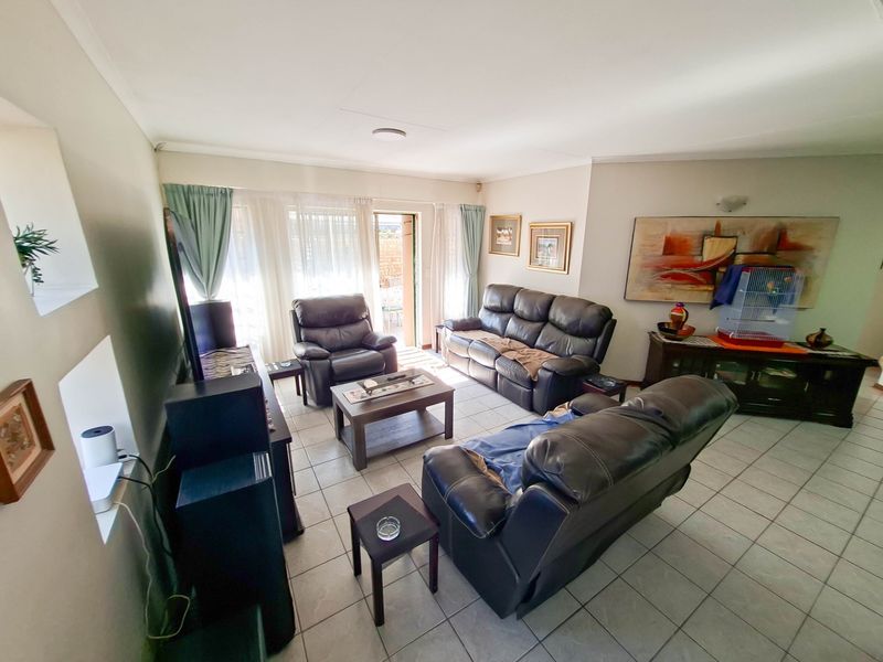 A spacious living room featuring neutral tiled flooring and a sliding glass door providing access to the outdoor area.