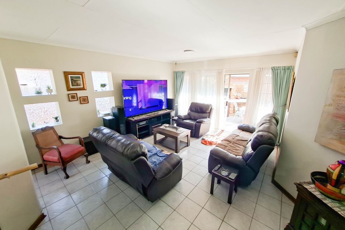 A spacious living room featuring tiled flooring, recessed lighting, and a sliding glass door providing access to the outdoor area.