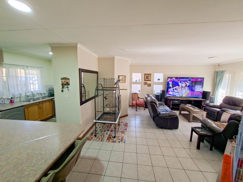Open-plan living area featuring tiled flooring, recessed lighting, and a functional kitchen space with built-in cabinetry and sink.