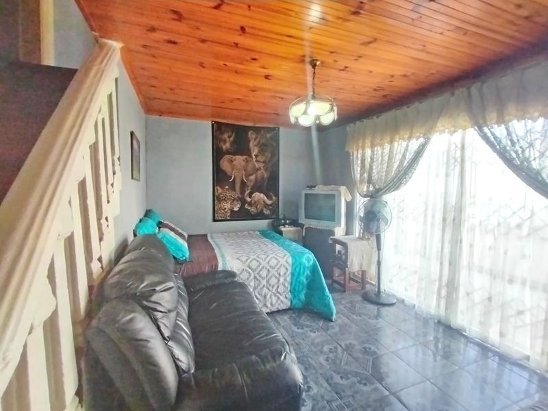 A bedroom featuring a timber-clad ceiling, tiled flooring, and a staircase, with access to an outdoor area through a sliding glass door.