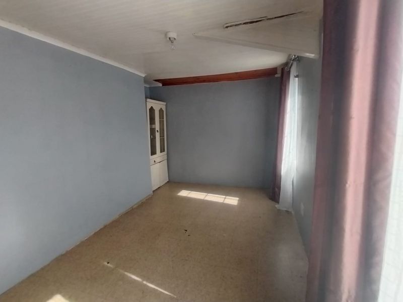 A vacant bedroom featuring a built-in cupboard, timber ceiling beam, and visible ceiling damage requiring repair.