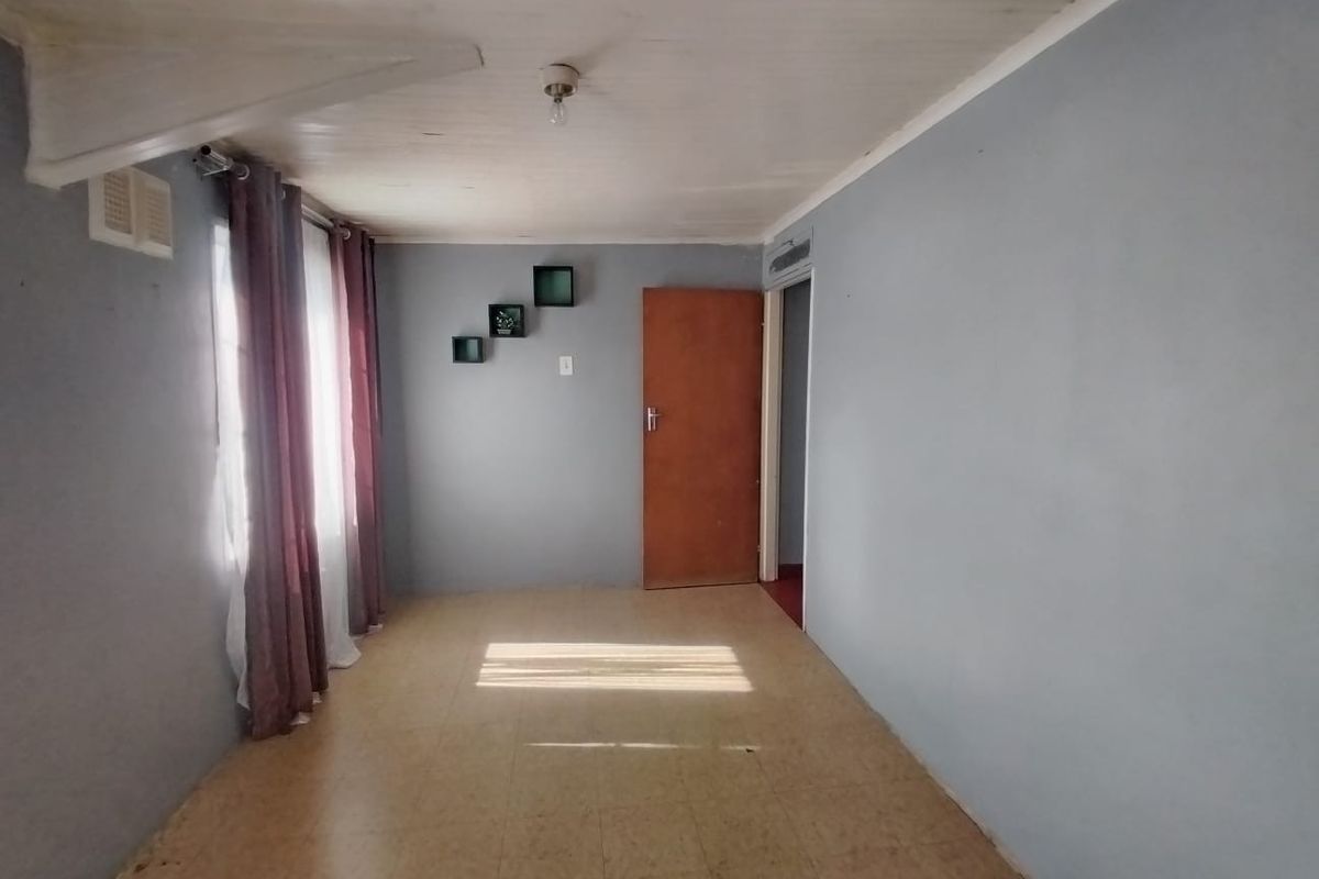 An empty bedroom featuring tiled flooring and a timber ceiling, offering a blank canvas for potential renovation or interior design updates.