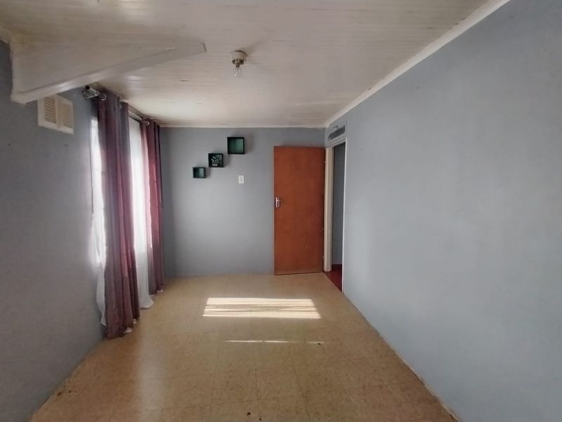 An empty bedroom featuring tiled flooring and a timber ceiling, offering a blank canvas for potential renovation or interior design updates.