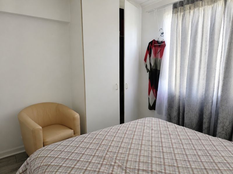 A functional bedroom featuring a built-in wardrobe and window with curtain rail, providing a neutral space ready for personalization.