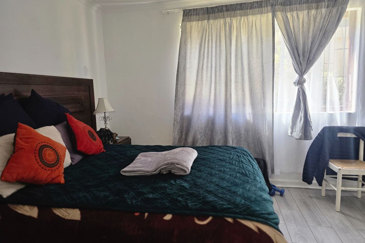 A bedroom featuring light-toned laminate flooring and window treatments, providing a neutral base for interior design updates.