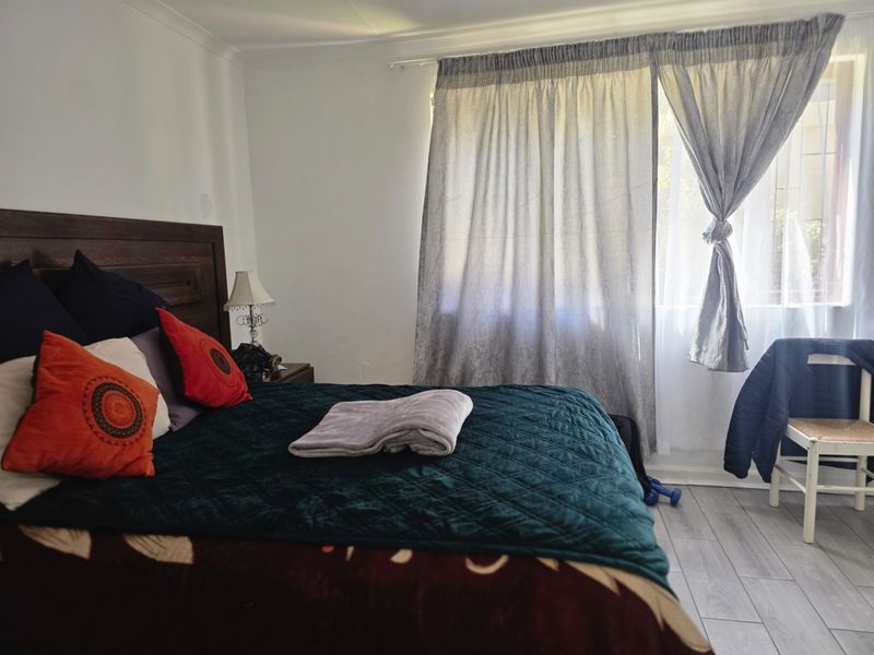 A bedroom featuring light-toned laminate flooring and window treatments, providing a neutral base for interior design updates.