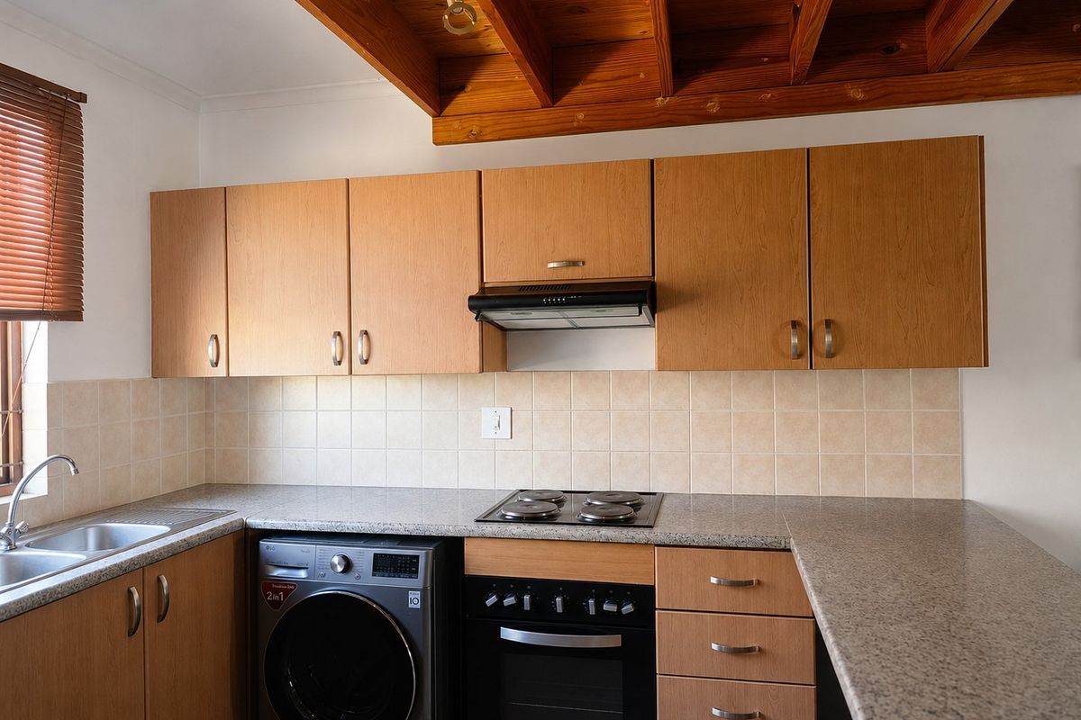 Functional kitchen featuring wood-finish cabinetry, granite-look countertops, tiled splashbacks, built-in oven and hob, and distinctive exposed timber ceiling beams.